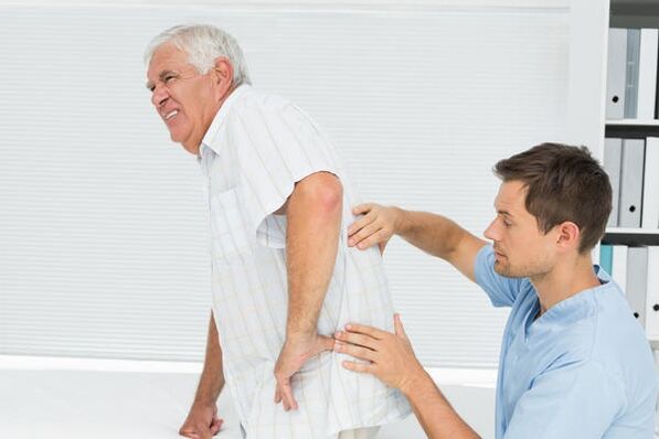 Elderly patient with low back pain visited by a doctor